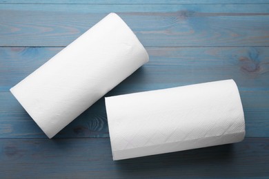 Photo of Rolls of paper towels on light blue wooden table, flat lay