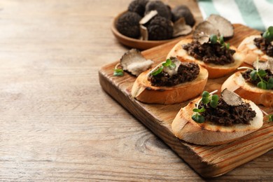 Photo of Delicious bruschettas with truffle sauce and microgreens on wooden table. Space for text