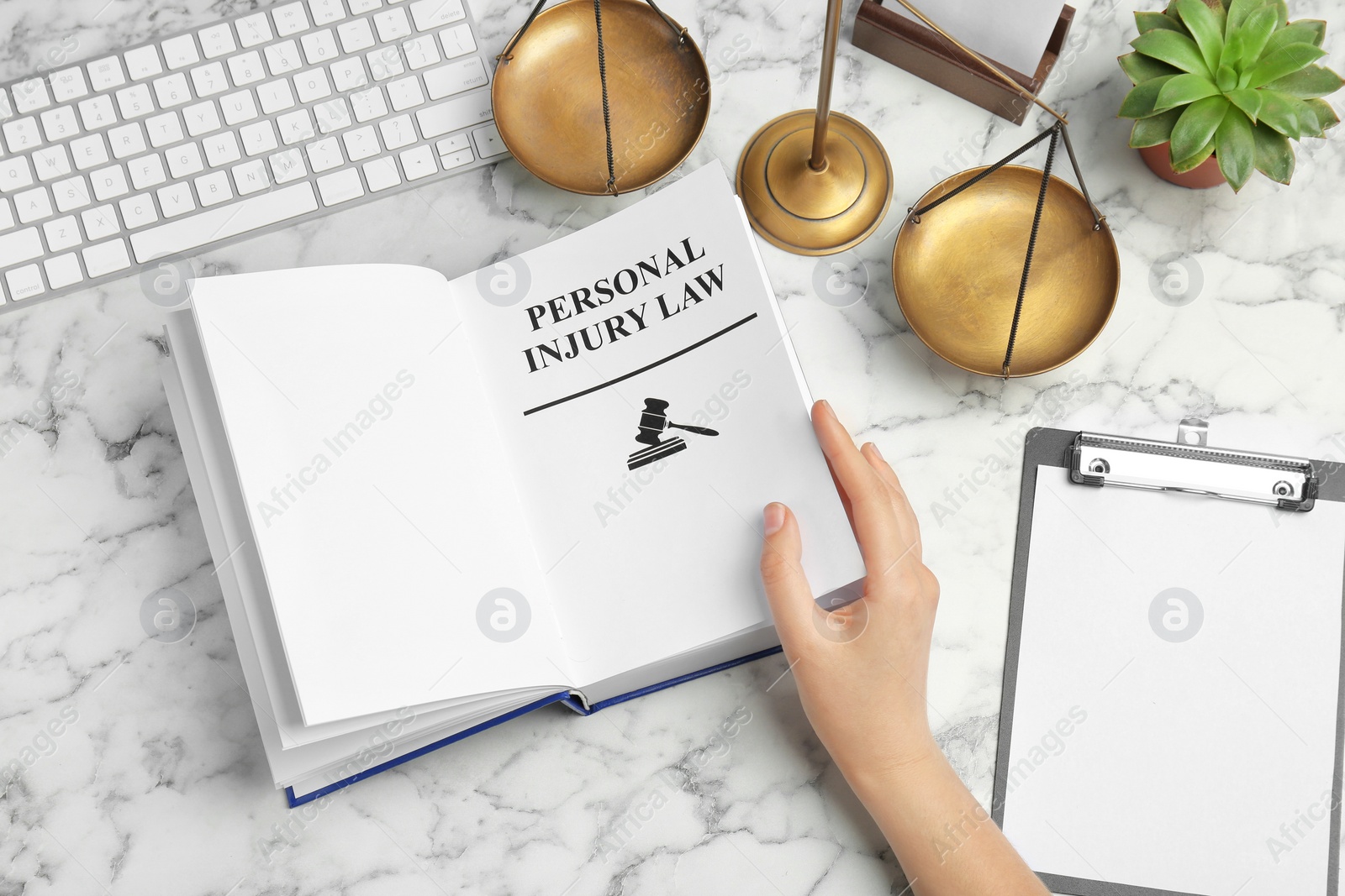 Photo of Woman turning page of book with words PERSONAL INJURY LAW at table, closeup