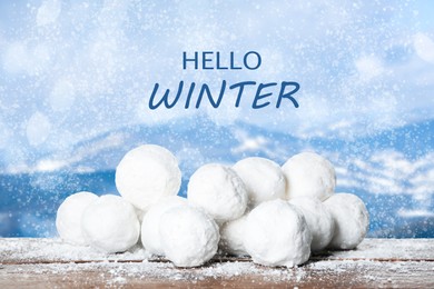 Image of Hello Winter. Snowballs on wooden surface and blurred view of mountains 