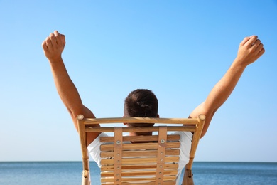 Photo of Young man relaxing in deck chair on beach near sea