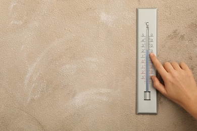 Photo of Woman with weather thermometer on beige background, closeup. Space for text