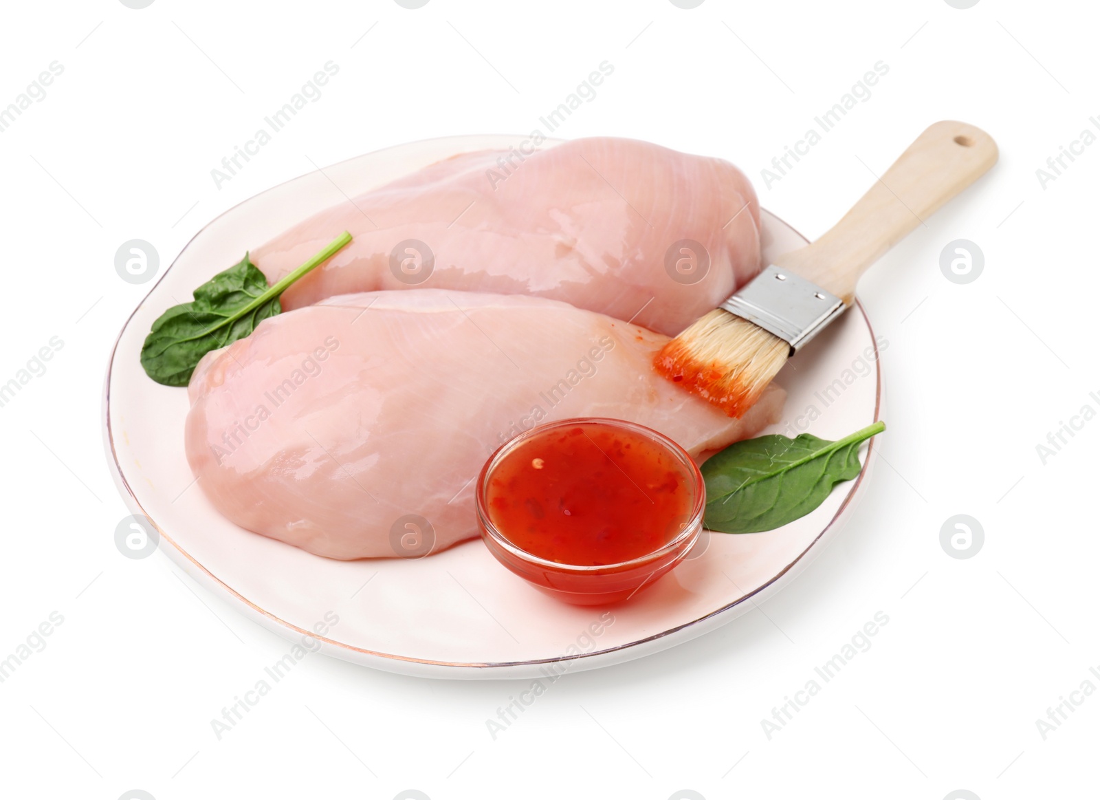 Photo of Marinade, basting brush and raw chicken fillets isolated on white