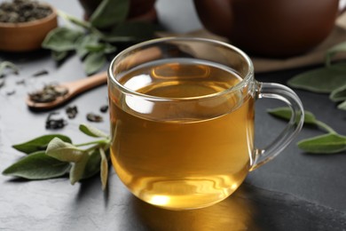 Photo of Cup of aromatic sage tea on black table