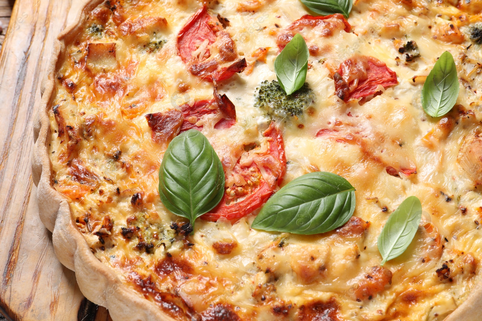 Tasty quiche with tomatoes, basil and cheese on wooden table, closeup Photo of Tasty quiche with tomatoes, basil and cheese on wooden table, closeup