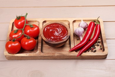 Plate with delicious ketchup in bowl, peppercorns and products on light wooden table, closeup. Tomato sauce