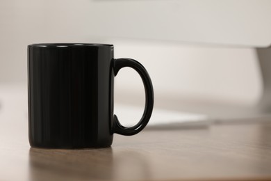 Photo of Black ceramic mug on wooden table at workplace. Space for text