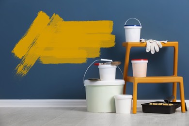 Image of Set with decorator's tools and paint on floor near blue wall