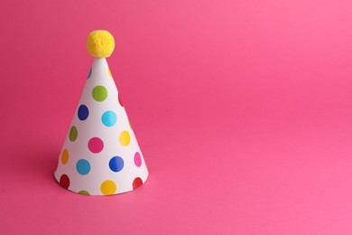 Photo of One beautiful party hat with pompom on pink background, space for text