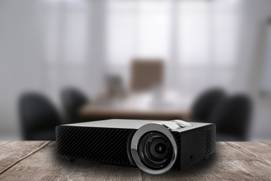 Modern video projector and blurred conference room on background