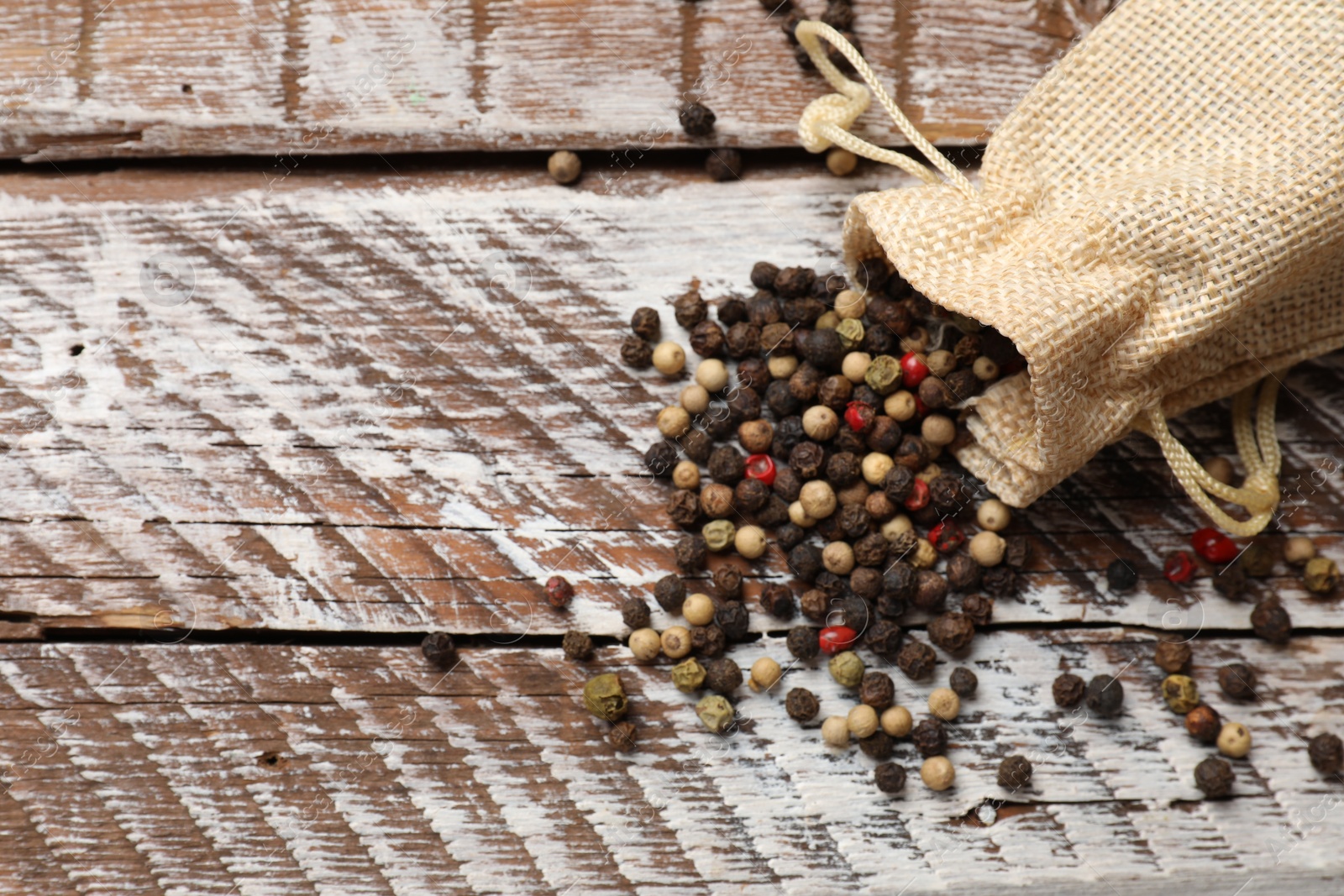 Photo of Aromatic spice. Different peppers in burlap bag on wooden table, top view. Space for text