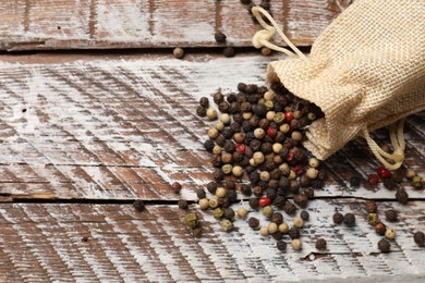 Photo of Aromatic spice. Different peppers in burlap bag on wooden table, top view. Space for text