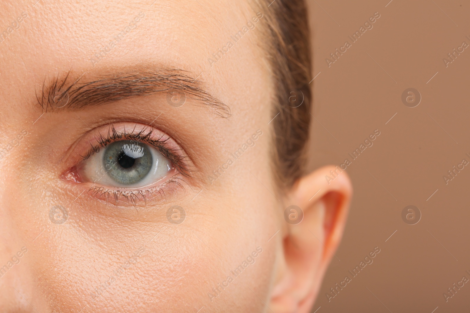 Photo of Woman with beautiful natural eyelashes on light brown background, closeup