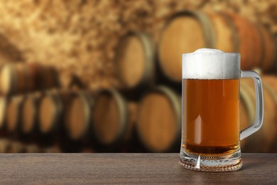 Image of Mug with fresh beer on wooden table in cellar, space for text