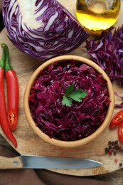 Photo of Tasty red cabbage sauerkraut and ingredients on wooden table, flat lay