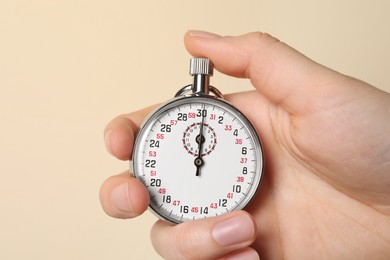 Woman holding vintage timer on beige background, closeup