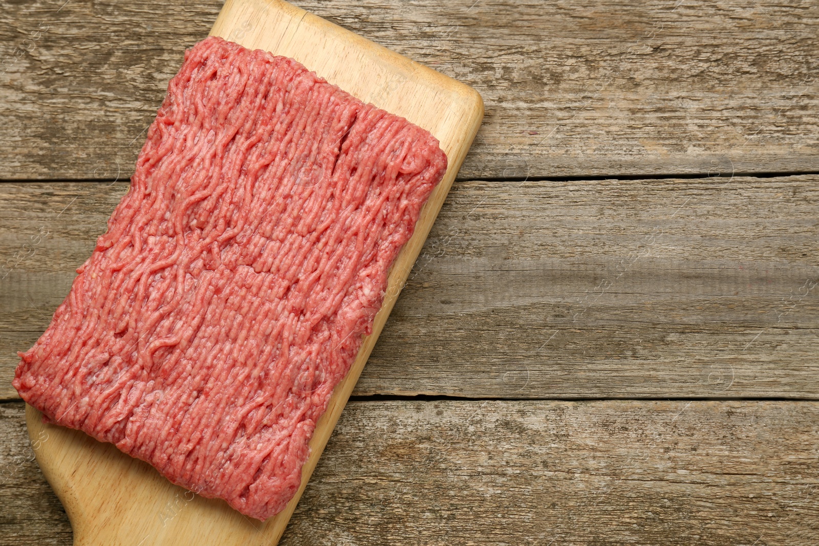 Photo of Board with raw fresh minced meat on wooden table, top view. Space for text