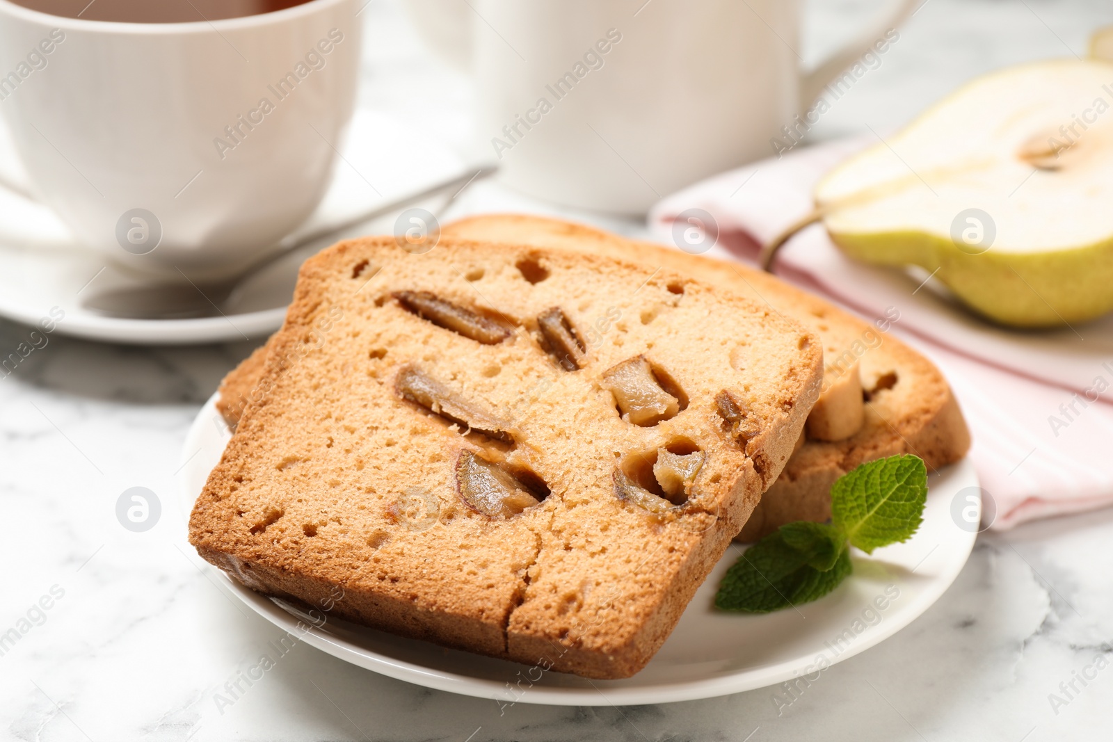 Photo of Slices of pear bread on white marble table, closeup. Homemade cake