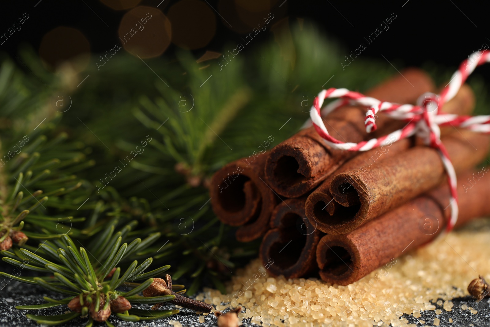 Photo of Different aromatic spices and fir branches on grey textured table, closeup