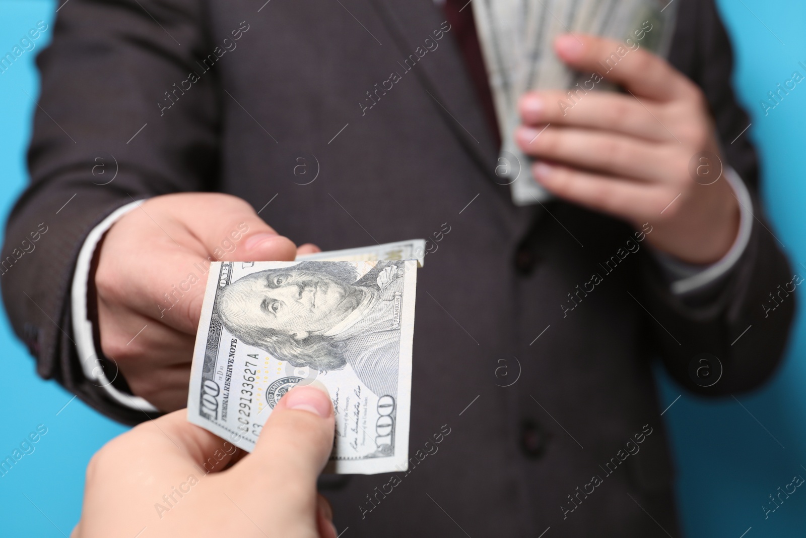 Photo of Man giving money to woman on light blue background, closeup. Currency exchange