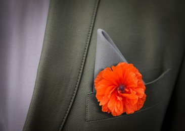 Image of Man with with red poppy flower in suit pocket, closeup view. Remembrance symbol