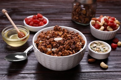 Photo of Tasty granola served with nuts, different ingredients on wooden table