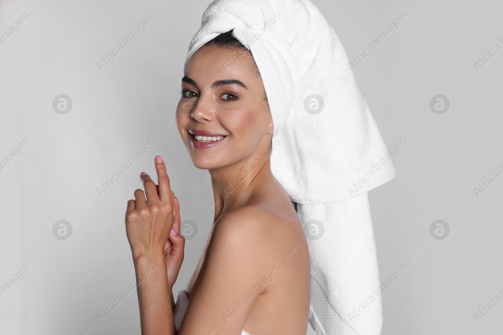 Photo of Beautiful young woman with towel on head against light background