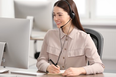 Photo of Hotline operator with headset and notebook working in office