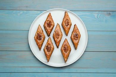 Photo of Delicious sweet baklava with walnuts on turquoise wooden table, top view