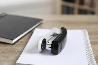 Photo of Stapler and notebooks on wooden table indoors, closeup