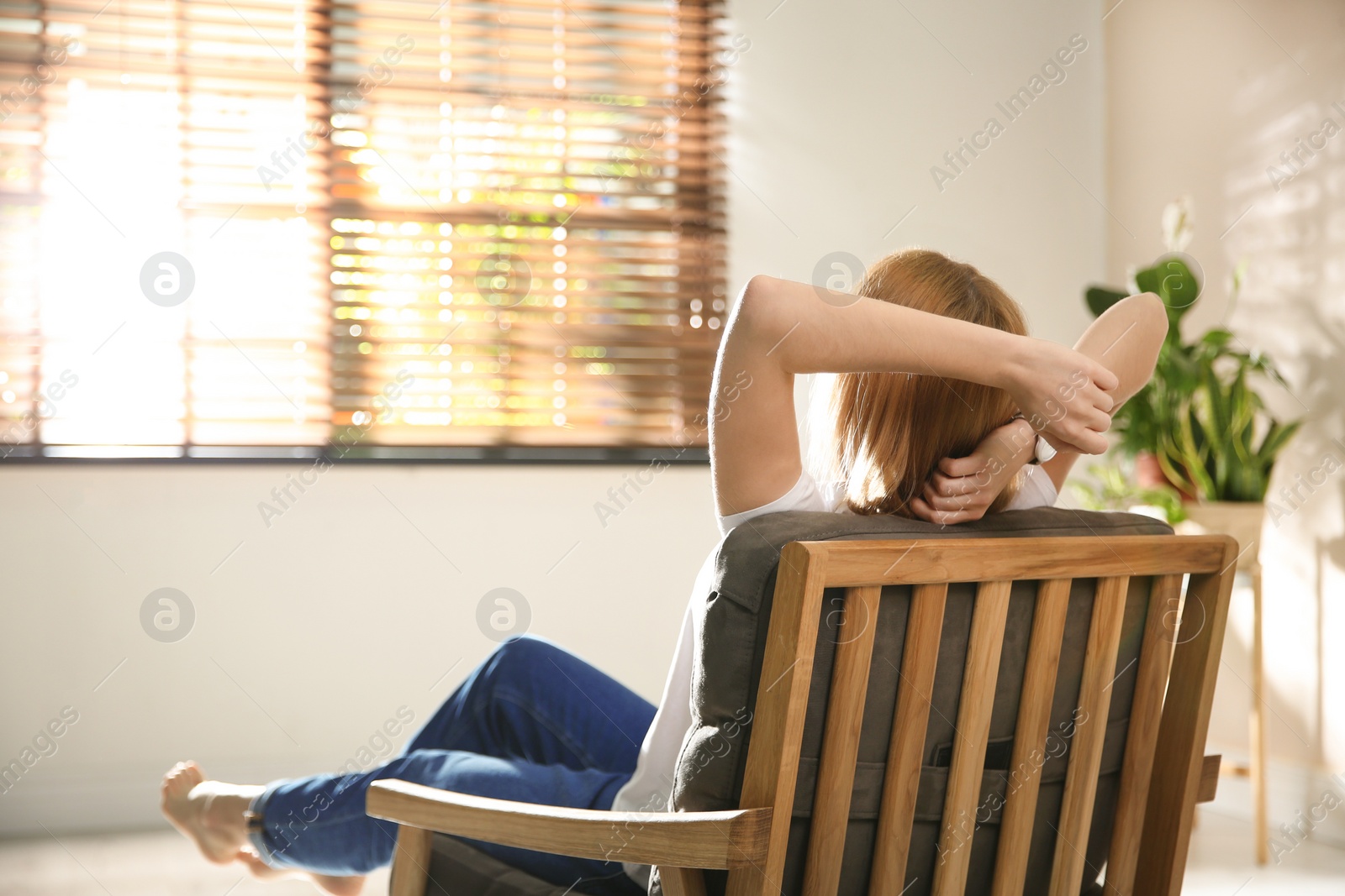 Photo of Young woman relaxing in armchair near window at home. Space for text