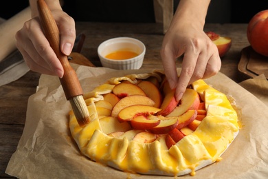 Photo of Woman making peach pie at table, closeup