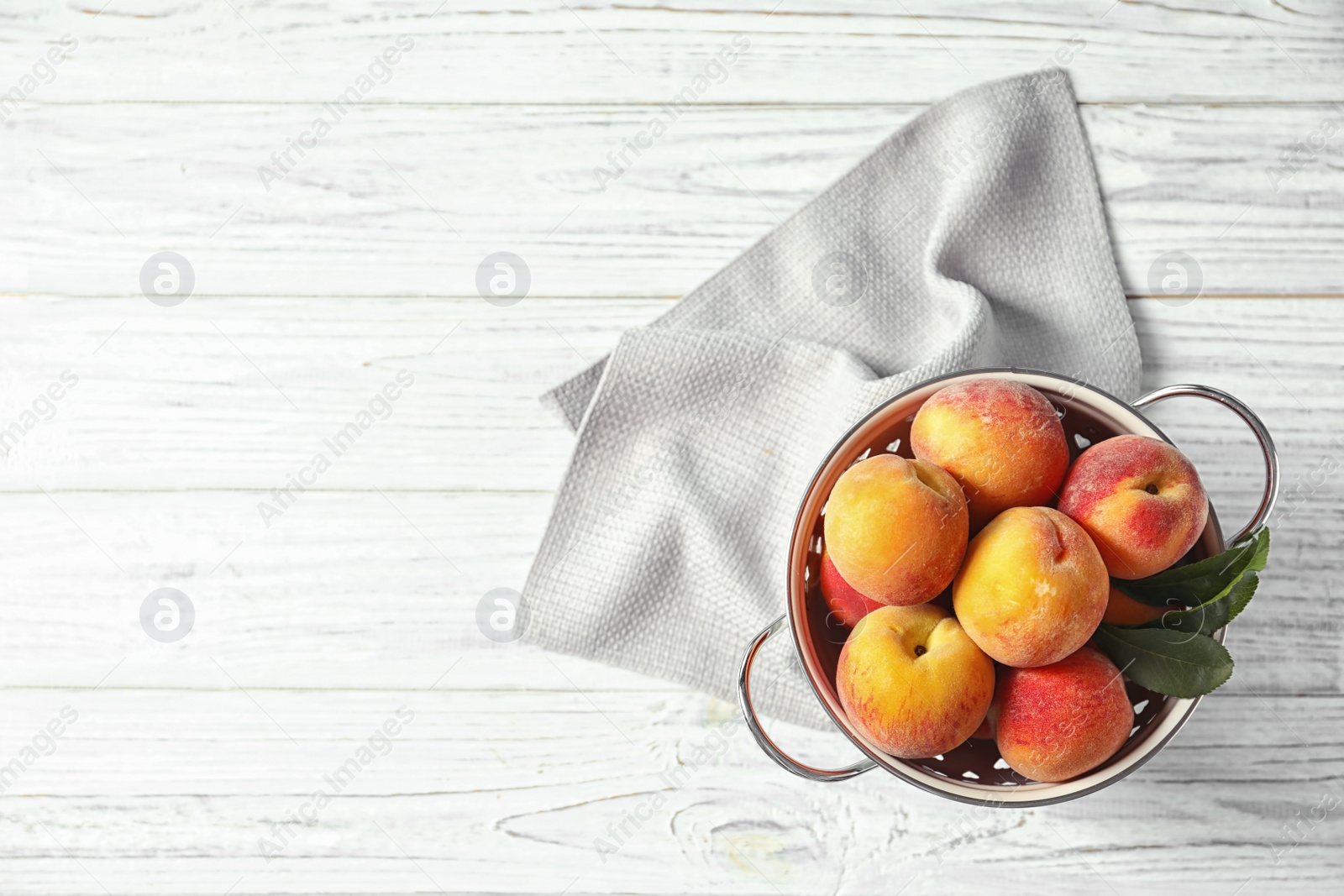 Photo of Colander with delicious ripe peaches on wooden background, top view