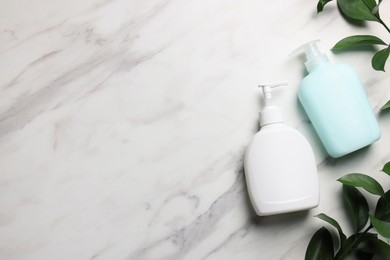 Photo of Dispensers of liquid soap and branches on white marble table, flat lay. Space for text