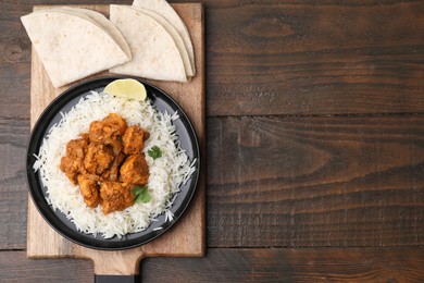 Photo of Delicious chicken curry with rice and tortillas on wooden table, top view. Space for text