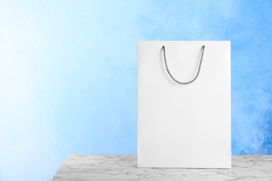 Mockup of paper shopping bag on table against color background