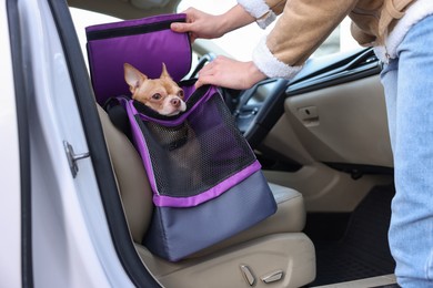 Photo of Owner transporting her dog, closeup. Chihuahua in pet carrier