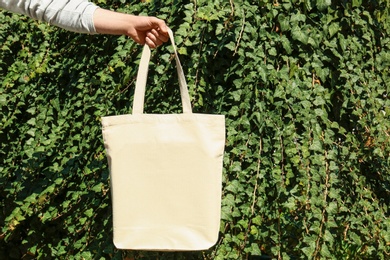 Photo of Woman holding eco bag outdoors, closeup. Mockup for design