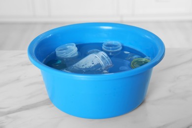 Photo of Basin with baby bottles and nipples on white marble table in kitchen