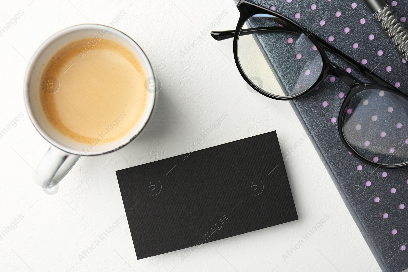 Photo of Blank black business card, cup of coffee, glasses and stationery on white table, top view. Mockup for design