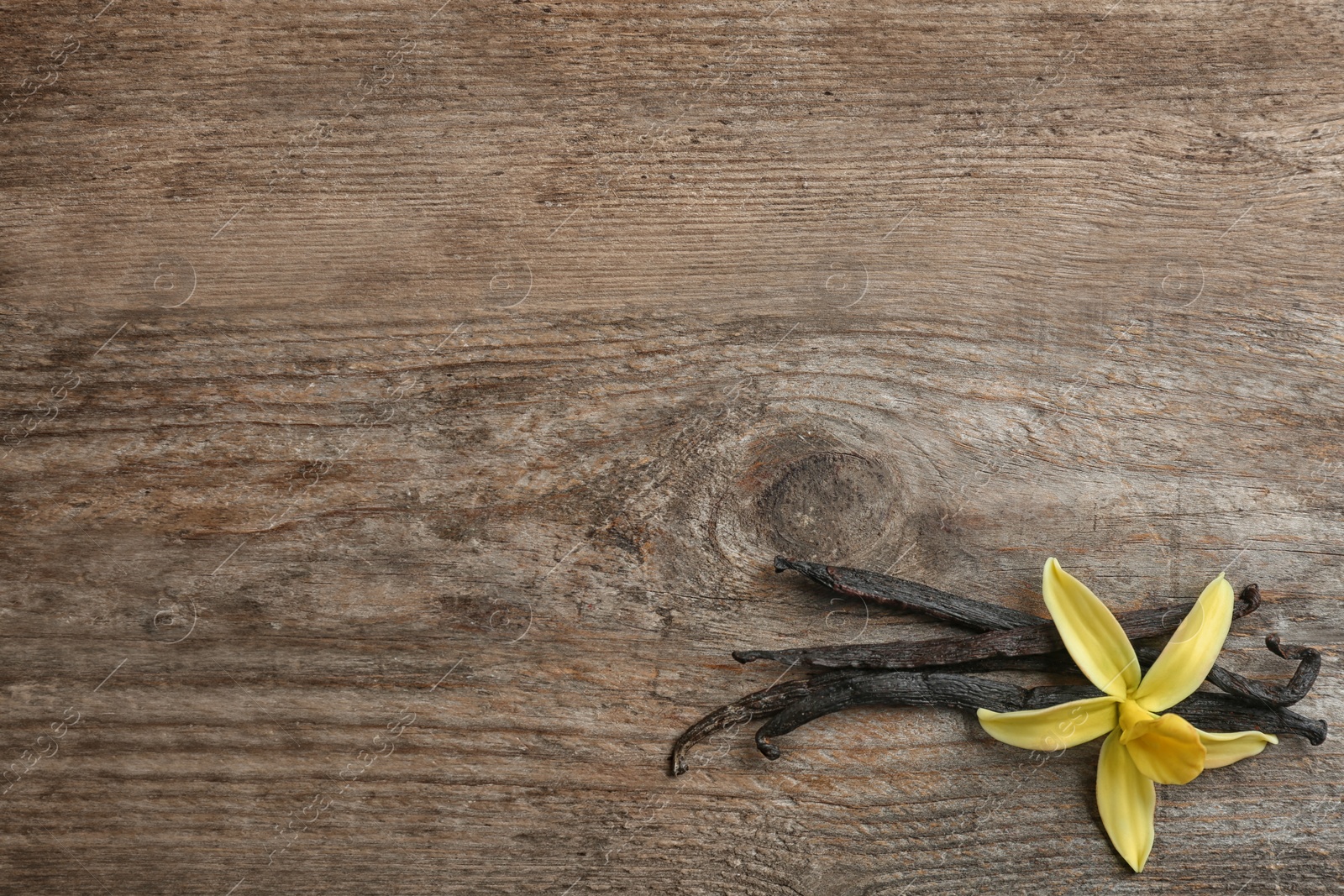 Photo of Flat lay composition with vanilla sticks and flower on wooden background. Space for text