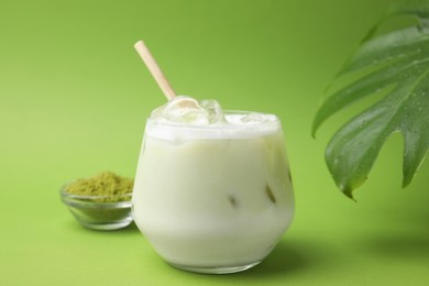 Photo of Glass of tasty iced matcha latte and powder on light green background