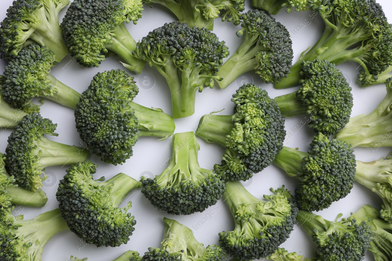 Photo of Many fresh green broccoli pieces on white background, flat lay