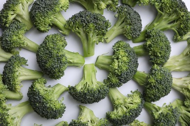 Photo of Many fresh green broccoli pieces on white background, flat lay