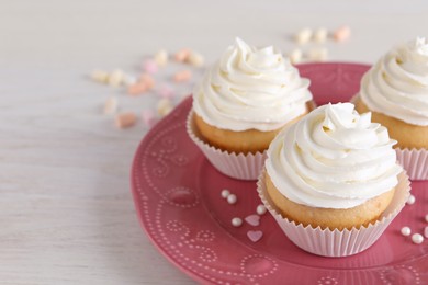 Delicious cupcakes with cream on white wooden table, closeup. Space for text