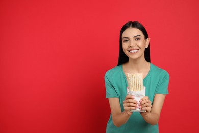 Photo of Happy young woman with delicious shawarma on red background. Space for text