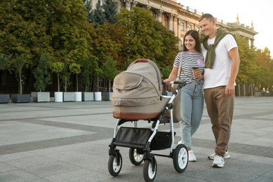 Happy parents walking with their baby in stroller outdoors