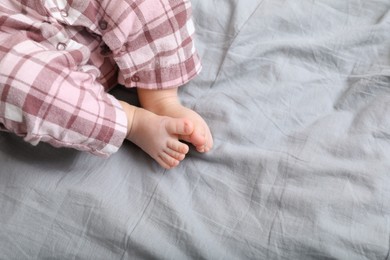 Photo of Little baby in pajamas on bed, closeup. Space for text