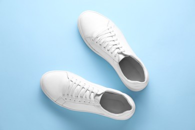 Photo of Pair of stylish white sneakers on light blue background, top view