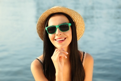 Beautiful young woman wearing stylish sunglasses near river